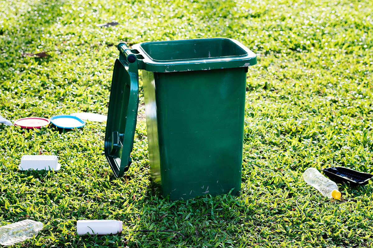 News - Rubbish scattered around a green wheelie bin.